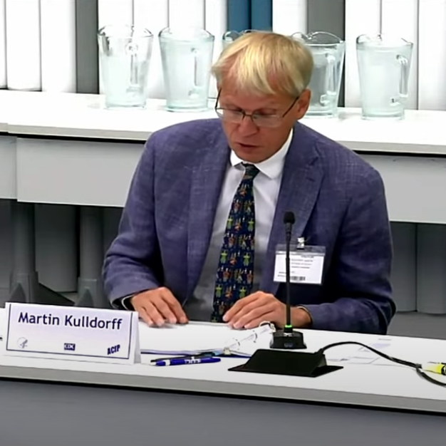A blonde man with glasses seated at a table.